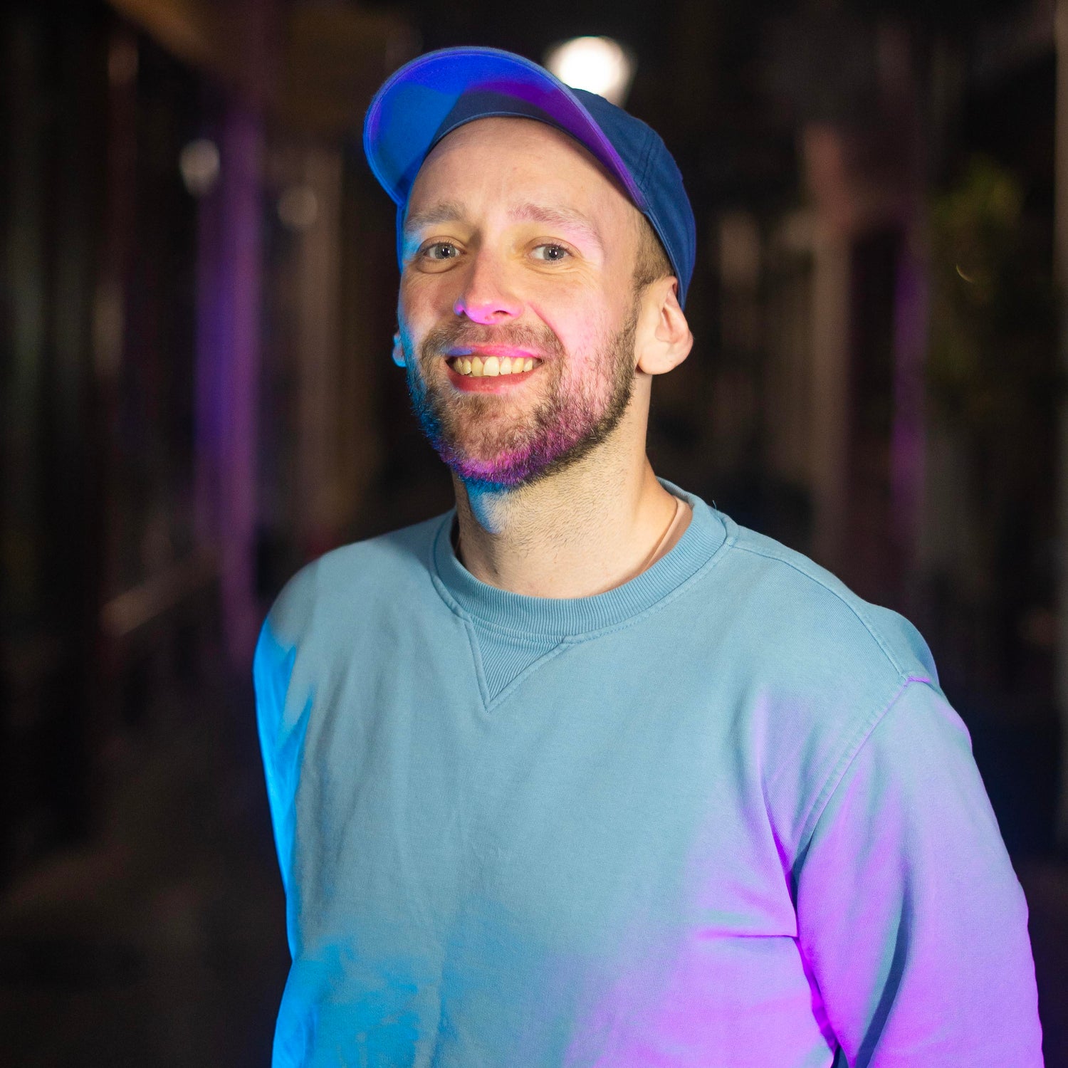 Jacob, in a blue cap and jumper, smiling at the camera.