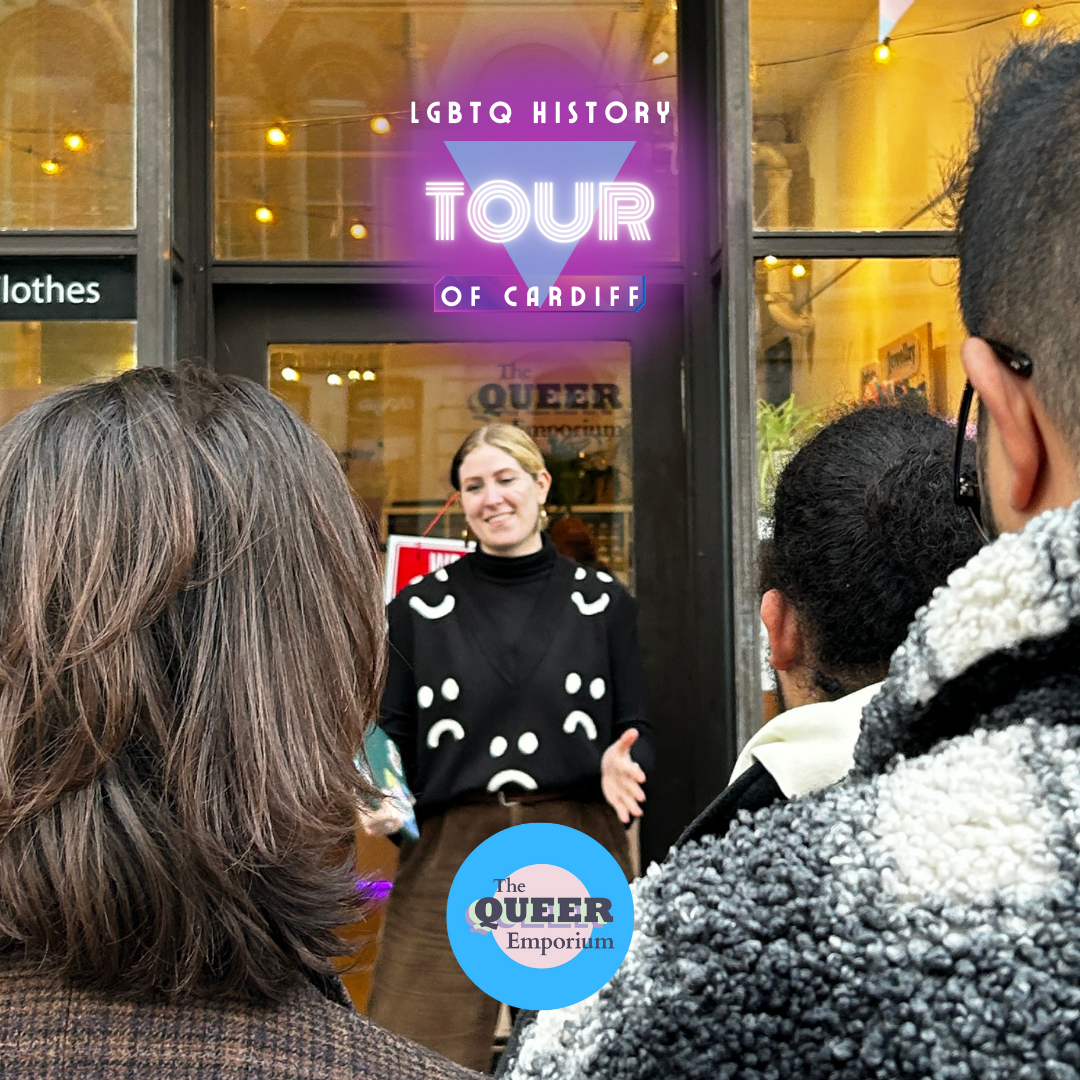 Outside The Queer Emporium, with a femme presenting, light-skinned tour guide presenting to a crowd of people.